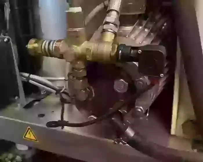 Internal view of a Nilfisk SH Truck Booster pump setup prior to installing an over-temperature protection system. The machine had previously suffered overheating issues due to continuous running caused by leaking trigger guns.